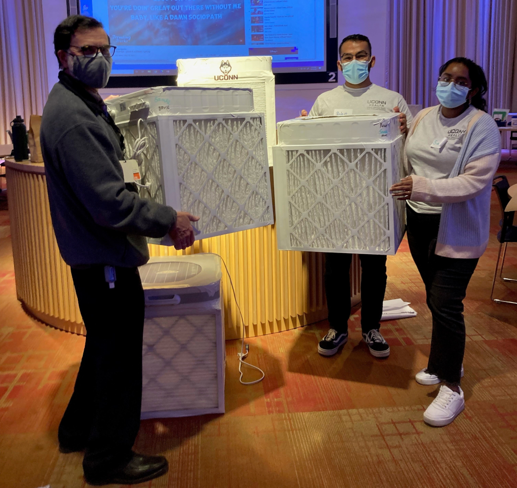 three people holding air purifiers